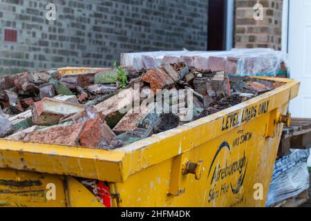 A yellow skip filled with discarded bricks. Stock Photo