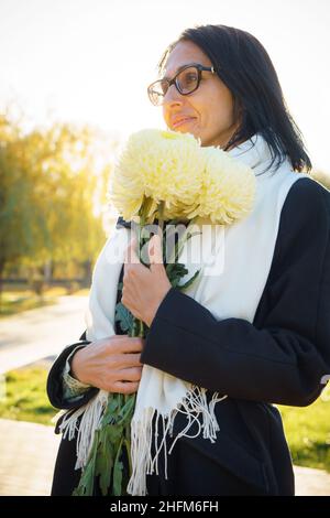 Profile side view portrait of attractive cheerful dreamy grey-haired middle-aged woman relaxing outdoors during sunny day Stock Photo