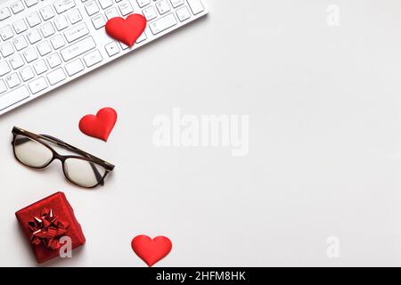 Desktop for Valentine's Day. Keyboard red hearts gift glasses on a gray table. Flat lay copy space top view Stock Photo