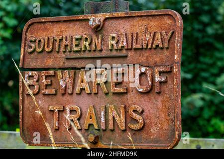 old beware of trains rust sign for southern railway. rusty and old fashioned infrastructure. beware of trains sign . vintage cast railway warning sign. Stock Photo