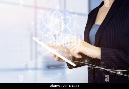 Atom molecule as concept for science. Hand touch white tablet with digital hologram molecule atom sign on light blurred background Stock Photo