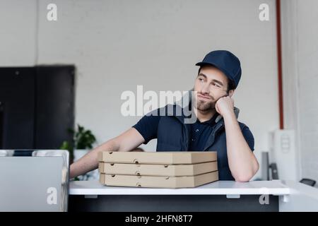 Upset courier standing near pizza boxes on reception in office Stock Photo