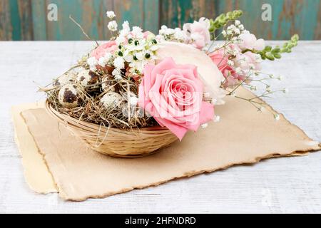 Easter floral table decoration with pink roses, matthiolas and ranunculus flowers in wicker basket. Party decor Stock Photo