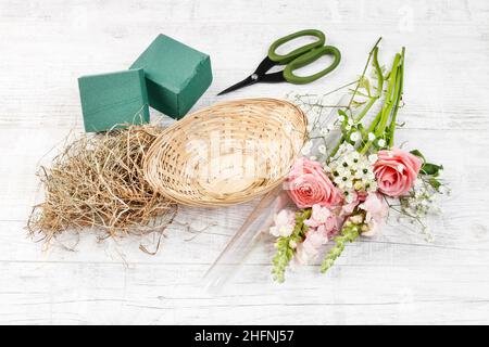 Florist at work: How to make easter floral table decoration with pink roses, matthiolas and ranunculus flowers in wicker basket. Step by step, tutoria Stock Photo