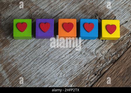 Colorful building blocks with red hearts on them. Rustic wooden background with copyspace. Stock Photo