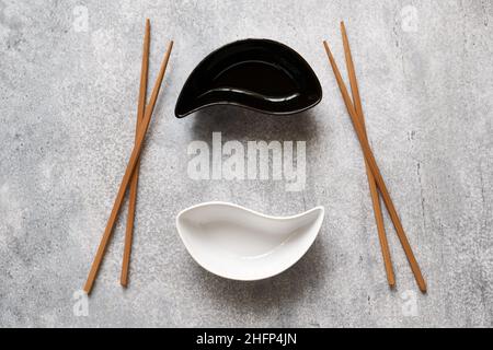 Ceramic Yin-Yang bowls and wooden bamboo chopsticks lie on the betton table Stock Photo