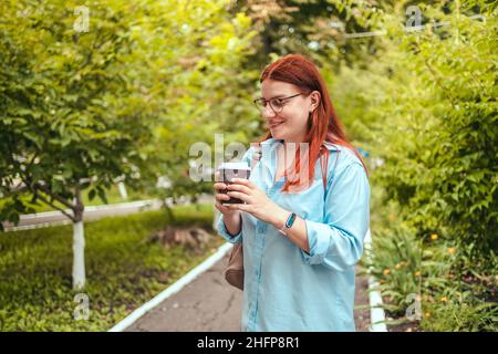 Portrait of Caucasian woman relaxing, hand holding takeaway paper cup of hot coffee with copy space. Stock Photo