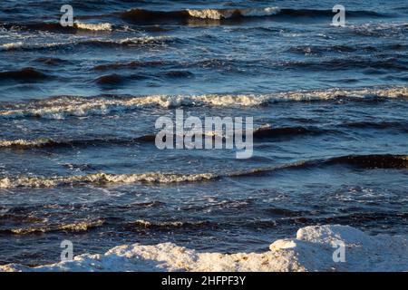 sea with white sand and blue water before storm. waves with white heads Stock Photo