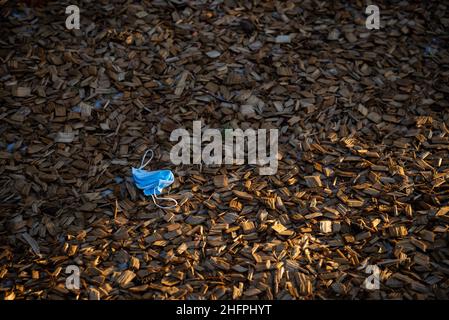 Coronavirus plastic waste environmental pollution. Disposable dirty face mask on ground, single use plastic trash on grass. How to dispose used medica Stock Photo