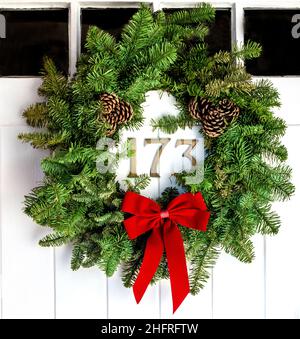 Traditional christmas holly wreath hanging on front door of 19th century cottage - Berkshire, England, UK Stock Photo