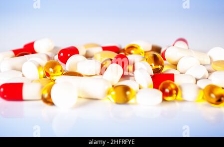 different kind of pills, tablets and capsules on light blue background with reflection close up Stock Photo