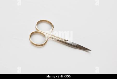 Small scissors. Steel nail scissors, gold hundle isolated on white background, design element. Stock Photo