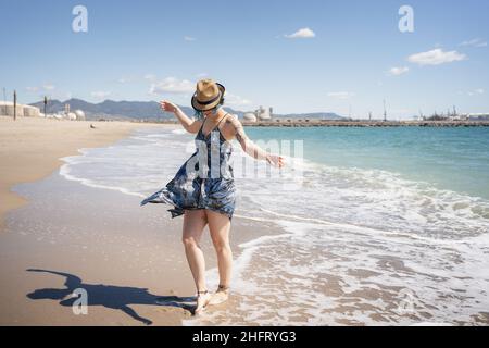 Happy woman dancing free on the beach with hat Stock Photo