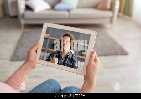 Female hands holding digital tablet, having video call with friend Stock Photo