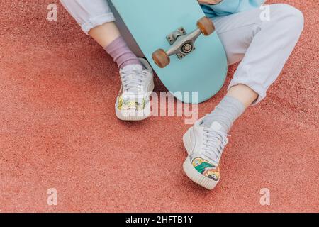 Unrecognizable person on skateboard, legs in sneakers with laces. Stock Photo