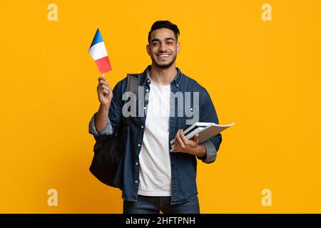 Cheerful arab guy with books and flag of France Stock Photo