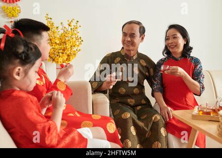 Senior couple spending Lunar New Year celebration with grandparents, drinking tea and talking Stock Photo