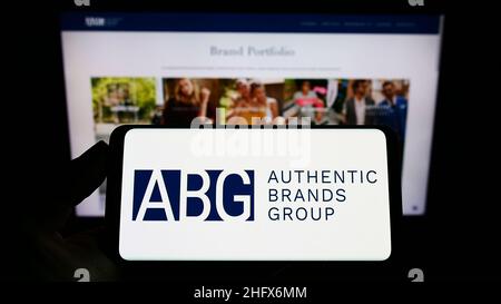 Person holding smartphone with logo of American company Authentic