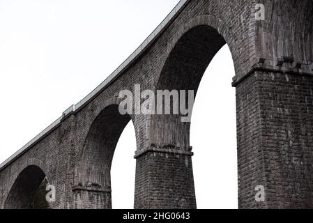 Architectural detail in close-up view from below of arches and columns pillars of stone brick railway bridge against high key lighting sky in Chamonix Stock Photo