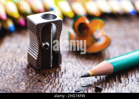 macro photograph of metallic pencil sharpener, under rustic wooden table, with space for text Stock Photo