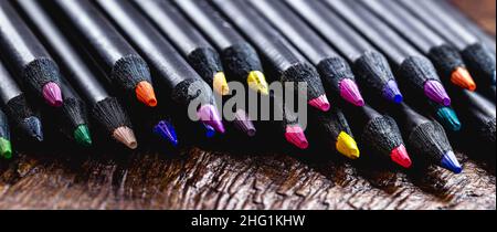 macro photograph of professional colored pencil, under rustic wooden table, with copyspace for text Stock Photo