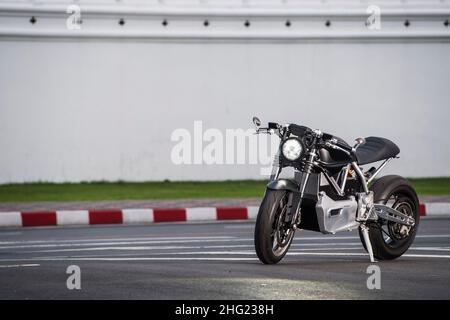 electric motorcycle parked against a white wall in Bangkok Stock Photo