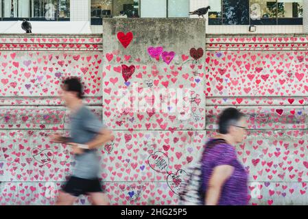 A section of the National Covid Memorial Wall covered in painted pink hearts and tributes to victims of the pandemic on the south bank in London