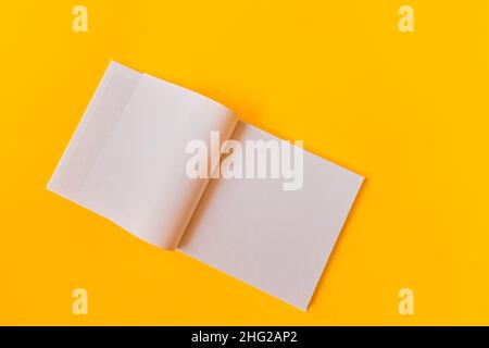 Notebook with white blank pages for notes on a yellow background. Stock Photo
