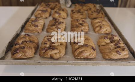 Close up of a baker holding hot tray with freshly baked buns with nuts. Close up of yummy bread products, foodporn concept. Stock Photo