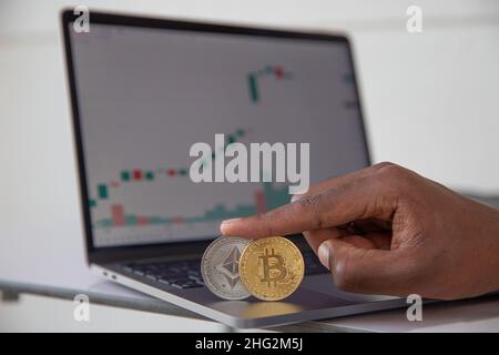 Close-up of a Bitcoin and an Ethereum coin in front of a candlestick chart with the value, These are the two main cryptocurrencies. Crypto investment Stock Photo