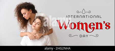 Girls of different nationalities and text INTERNATIONAL WOMEN'S DAY on grey background Stock Photo