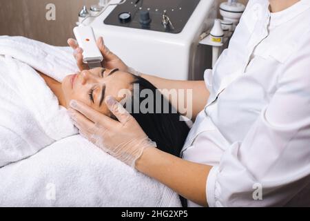 Caucasian woman getting ultrasound skin cleaning at spa salon. Facial skin treatment. Beauty face. Facial skincare. Rejuvenation treatment. Stock Photo