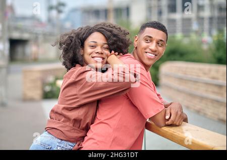 Woman leaning on back of man standing sideways to camera Stock Photo