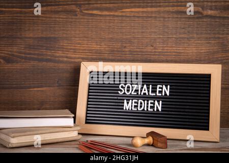 Social Media. Text in German. Colored pencils and a stack of books on the table. Stock Photo