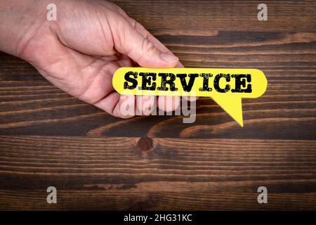 SERVICE. Yellow speech bubble on a dark wood texture background. Stock Photo