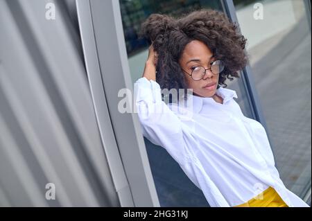 Woman leaning on building looking to side pensive Stock Photo
