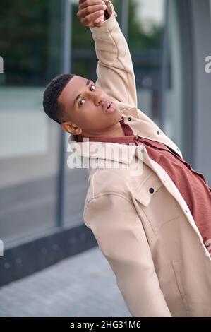 Man looking at camera dancing on street Stock Photo