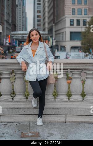 Shallow focus of a pretty happy smiling Caucasian female leaning on a decorative barrier outdoors Stock Photo