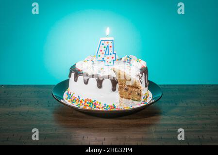 A birthday cake, missing a slice, bears a candle in the shape of the number 4. Stock Photo