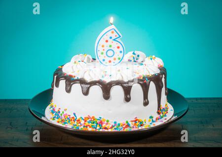 A birthday cake bears a candle in the shape of the number 6. Stock Photo