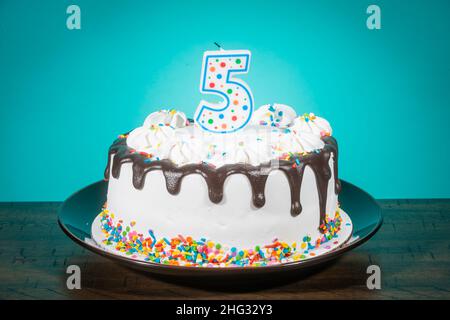 A birthday cake bears a candle in the shape of the number 5. Stock Photo