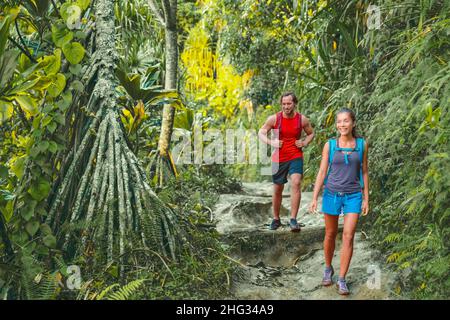 Hawaii hiking hikers on Kalalau trail hike walking in rainforest with tropical trees. Tourists couple with backpacks walking outdoor in Kauai island Stock Photo