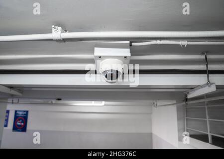 CCTV camera is installed on the car parking, ceiling for monitor and safety system control in dark low light atmosphere. Stock Photo