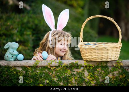 Happy easter day. Child with bunny ears. Kids boy hunting easter eggs in park. Stock Photo