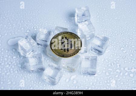 Bitcoin coin middle melting ice cubes and water drops on light background Stock Photo