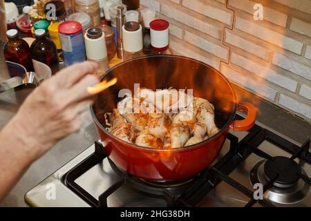 Flamber chicken legs in saucepan on the gas stove Stock Photo