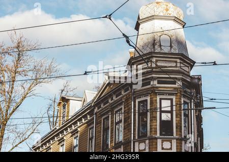 An old wooden house similar to a church, next to which the tram line wires pass. View from below against the blue sky. Stock Photo