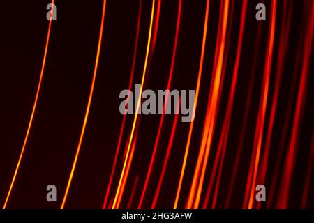 Bright red diagonal vertical lines of rays on a dark background. Abstract backdrop. Stock Photo