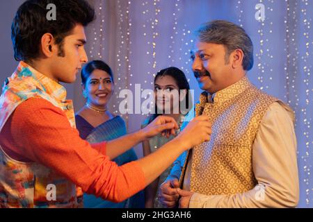 Son helping his father while wearing  cloth on Diwali Stock Photo