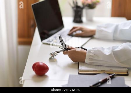 Close-up, side view, A doctor researching medical papers on laptop computer at her office clinic. Stock Photo